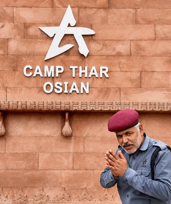 Camp Thar Osian welcoming guard in front of heritage carved sandstone wall